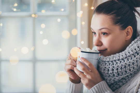 Close up of woman drinking hot chocolate next to the window. Winter theme 