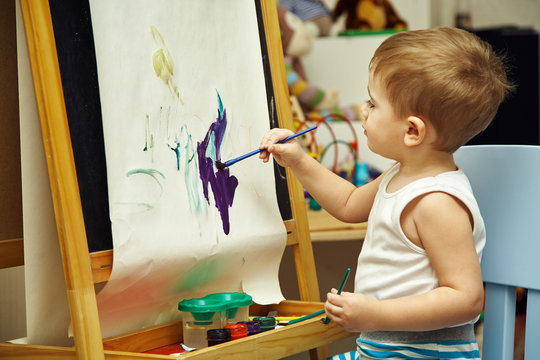 little boy paints a on easel