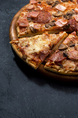 Pizza with cheese and sausage on a dark background, vertical, top view