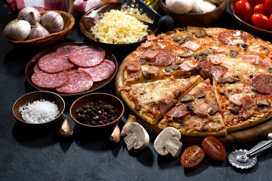 pizza with salami and ingredients on a dark background
