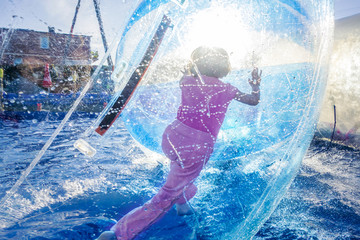 Young girl playing inside a floating water walking ball.