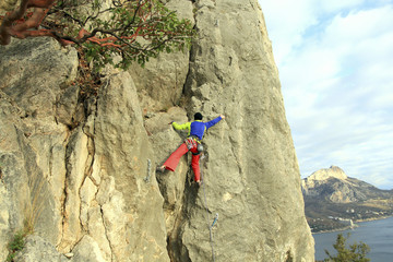 Rock climber ascending a challenging cliff. Extreme sport climbing. Freedom, risk, challenge, success.