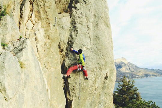Rock climber ascending a challenging cliff. Extreme sport climbing. Freedom, risk, challenge, success.
