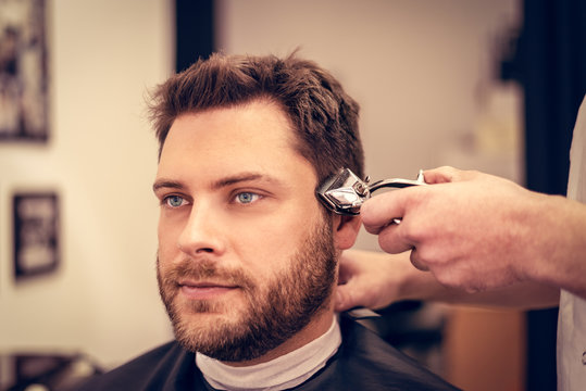 Barber cutting the hair of a man using a vintage hand operated hair clipper