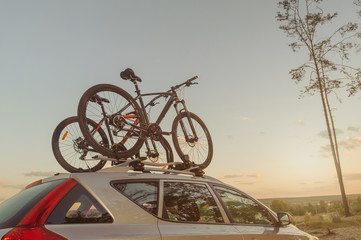 Car is transporting bicycle on the roof. Sunset.