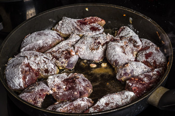 The cook prepares the fried liver in a frying pan on an induction cooker