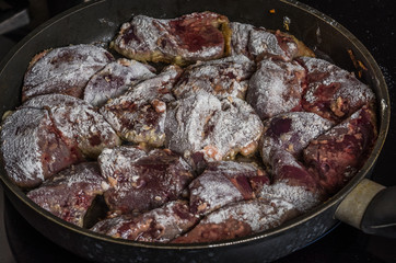 The cook prepares the fried liver in a frying pan on an induction cooker