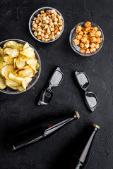 Cinema food. Crisp, popcorn, rusks near glasses on black background top view