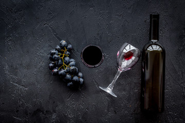 Drink wine concept. Bottle, glass, grape on black background top view