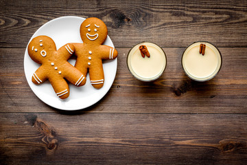 Eggnog for christmas evening. Two glasses near gignerbread cookie on dark wooden background top view copyspace