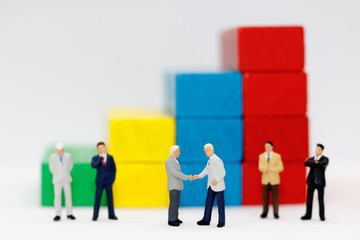 Miniature people handshake with step of Wood block stack.  agreement, investment, partnership and business concept