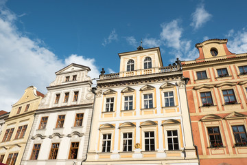 Row of vernacular houses surrounding Old Town Square in Prague, Czech Republic. Looking up at traditional historic architecture in Prague. Dutch gabled roof, dentils, and stone balcony. Blue skies.