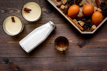 Ingredients for eggnog. Eggs, milk, cinnamon, whiskey on dark wooden background top view