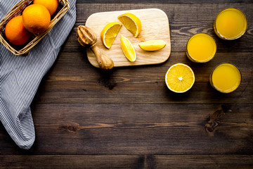 Squeeze juice from oranges. Juicer and slices of oranges on dark wooden background top view copyspace