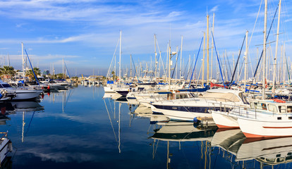 Fototapeta na wymiar Reflection of boats laying in a marina at Larnaca, Cyprus. Blue sky and sea background.