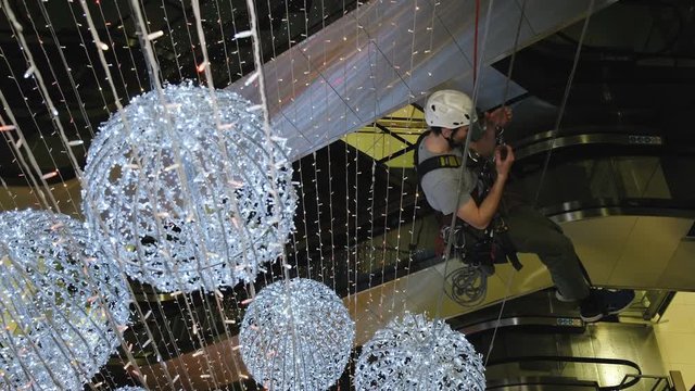 Industrial climber mounts Christmas decorations in the unsupported space in the shopping center