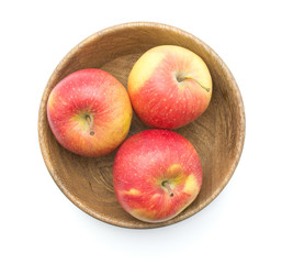 Three apples (Evelina variety) in a wooden bowl top view isolated on white background red yellow.