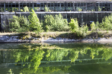 Abandoned industrial hall in Romania, outside view, reflected in a river