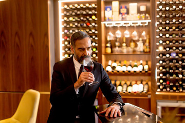 Handsome mature man tasting red wine