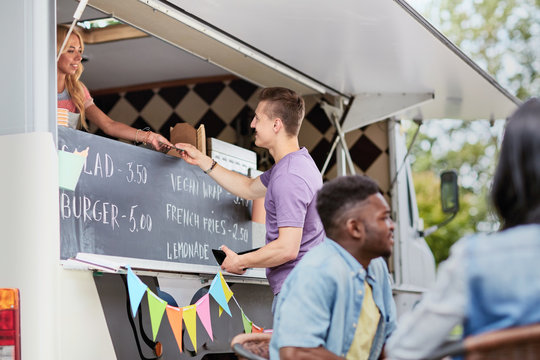 customer paying money to saleswoman at food truck