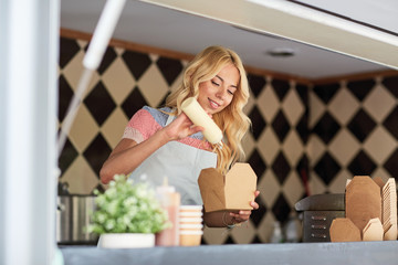 happy saleswoman making wok at food truck