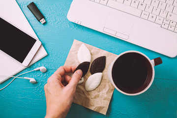 Office table desk. Workspace with diary, plant, headphones, coffee, pencils on blue table. Top...