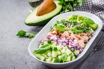 Fresh summer avocado tuna cucumber salad on concrete background. Selective focus, copy space.