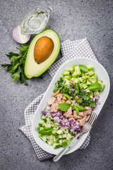 Healthy avocado fish cucumber salad on concrete background. Top view, space for text.