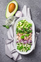 Olive oil avocado tuna cucumber salad on concrete background. Top view, space for text.