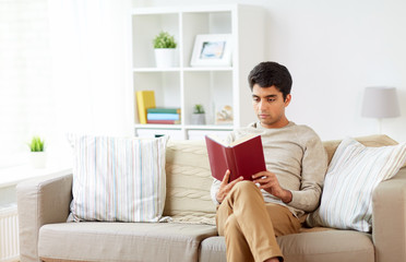 man sitting on sofa and reading book at home