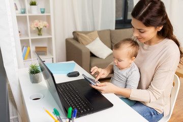 happy mother with baby and laptop working at home