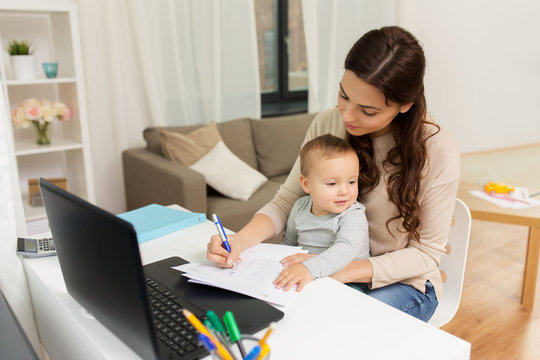happy mother with baby and papers working at home