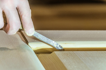 Carpenter spatula puttying wooden surface of the door leaf. Woodworking carpenter hand tool in...