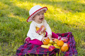 Baby with fruits on the green grass