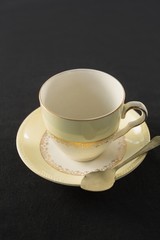 Empty cup with saucer and spoon on black background