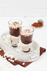 Warm cocoa in glasses with marshmallow, crocahet decorations, brown and beige napkins on white wooden background. Hot chocolate. Sweet drink. Close up photography. Vertical banner