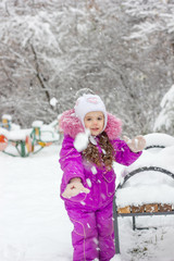 Fototapeta na wymiar Little girl plays snowballs at winter day outdoors.