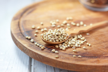 Obraz na płótnie Canvas Coriander seeds in a wooden spoon over kitchen board.