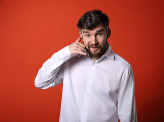 Excited funny surprising business man showing call me gesture with happy smiling on bright red background. Closeup