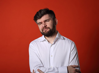 Fototapeta premium Unhappy tired thinking bearded business man in white shirt on red background. Portrait of stress