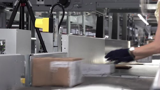 Lady correcting parcels on conveyor - time lapse motion blur
