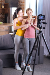 Yoga lesson. Nice positive young women standing in front of the camera and practicing yoga while recording yoga lesson