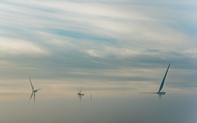 Parque e&oacute;lico al amanecercon cielo nuboso