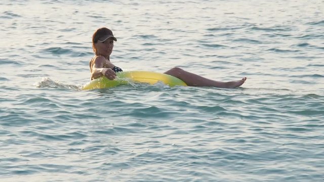 Girl on the inflatable ring. A happy girl is floating in a circle in the sea.
