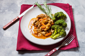 Beef goulash with vegetables and broccoli on rustic concrete background