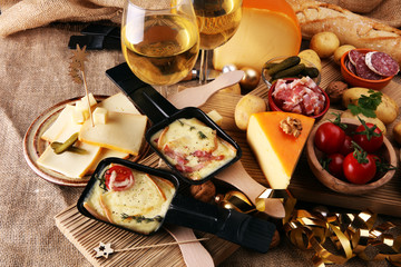 Delicious traditional Swiss melted raclette cheese on diced boiled or baked potato served in...
