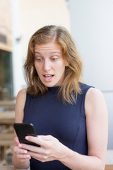 Shocked Young Woman Using Smartphone Outdoors