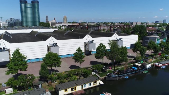 Aerial downtown Utrecht city first showing canal with houseboats and small recreational boat moving over the water in further background showing Utrecht skyline modern skyscraper and Dom Tower 4k