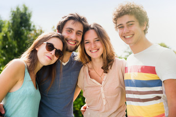 Portrait of four young people outside, they look at the camera