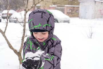 The boy holds snow in hands